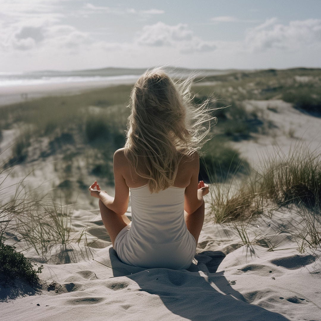 blond kvinna sitter i lotusposition på stranden