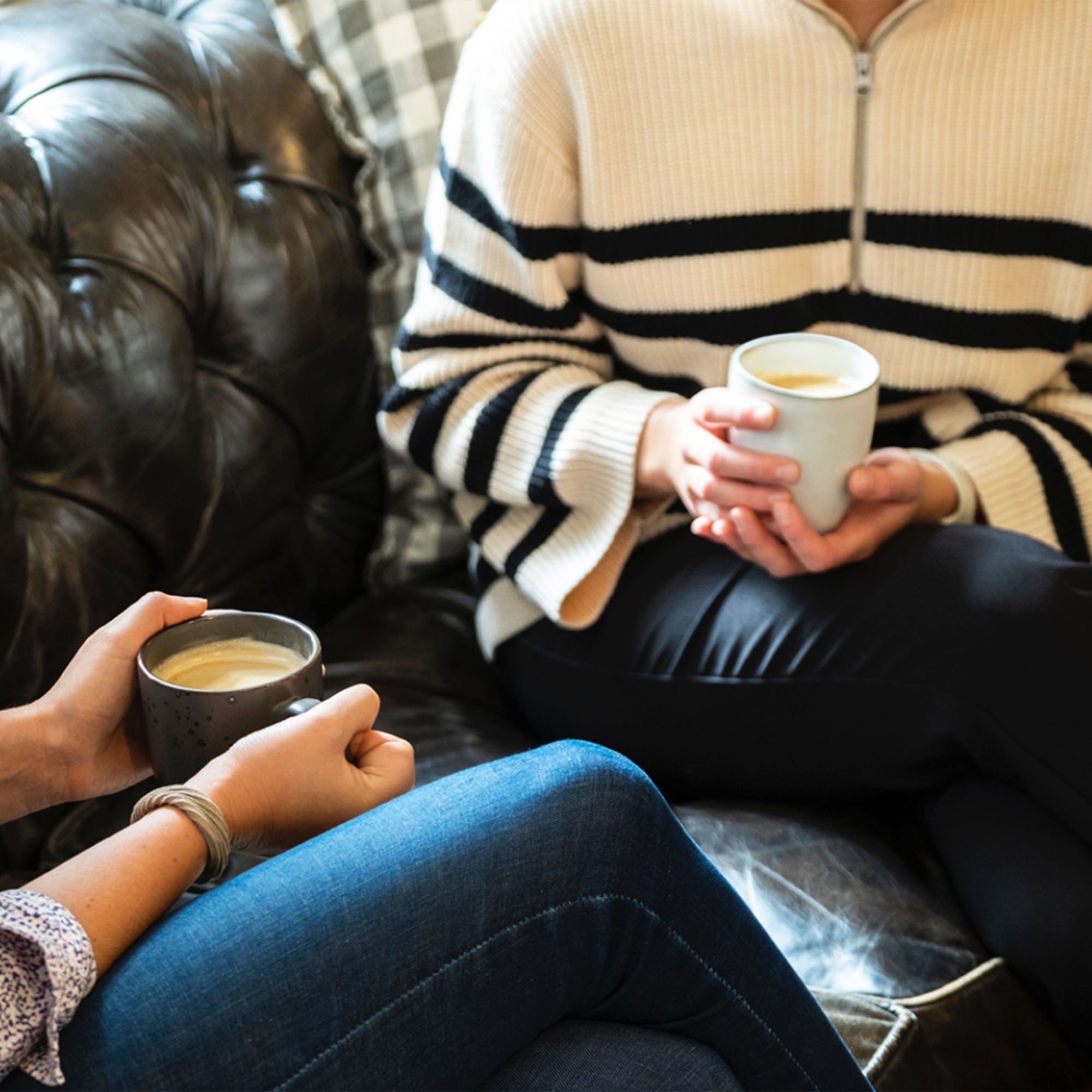 Två personer sitter i en soffa och njuter av varsin kopp kaffe i handen